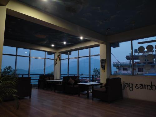 a room with chairs and tables and windows at Jay sambhoo pumdikot lodge restaurant and cafe in Pokhara