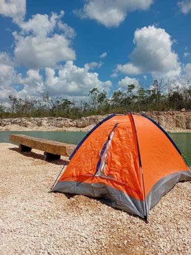an orange tent on the ground next to a bench at Camping Kitam in Tulum