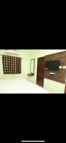 a bedroom with a bed and a flat screen tv at Galaxy beach residency in Velankanni