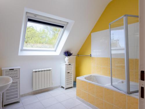 a bathroom with a tub and a sink and a window at Maison De Charlie 4 personnes in Trégastel