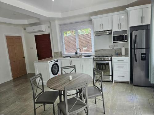 una cucina con mobili bianchi, tavolo e sedie di Agape Suites-Room 2-Ground Floor a Soufriere