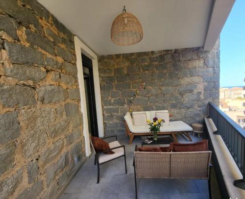 un patio avec une table et des chaises et un mur de briques dans l'établissement T3 Centre Propriano, à La Celle-sous-Gouzon