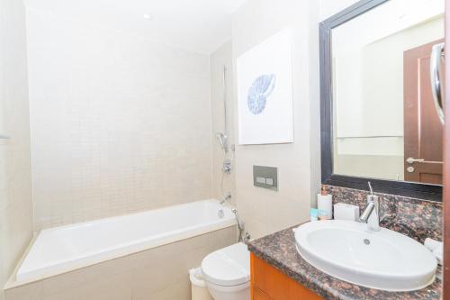 a bathroom with a sink and a tub and a toilet at Voyage Saadiyat Island Retreat in Abu Dhabi