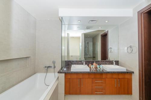 a bathroom with two sinks and a tub and a mirror at Voyage Saadiyat Island Retreat in Abu Dhabi