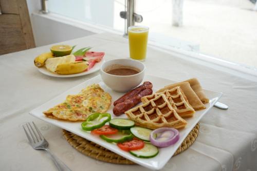 a plate of breakfast food with eggs sausage and waffles at Villa Ramo in Kiwengwa