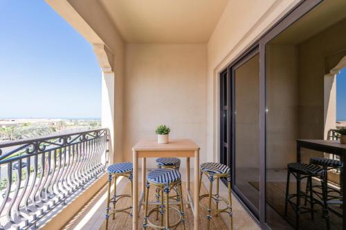 a balcony with stools and a table with a view at Voyage Saadiyat Island Retreat in Abu Dhabi