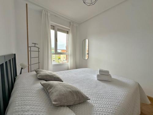 a white bedroom with a bed with pillows and a window at La Espina, en Somo - 30024 in Somo