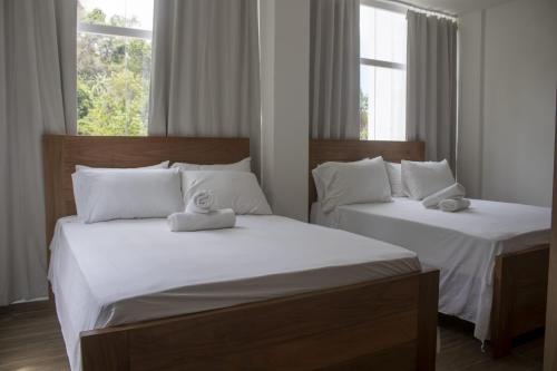 two twin beds in a room with two windows at Refugio Verde Las Terrenas in Las Terrenas
