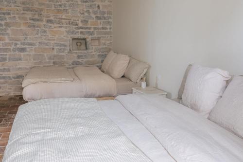 two beds in a room with a brick wall at Gîte Guillaumand in Pompignan