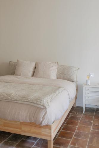 a bed in a bedroom with a white wall at Gîte Guillaumand in Pompignan