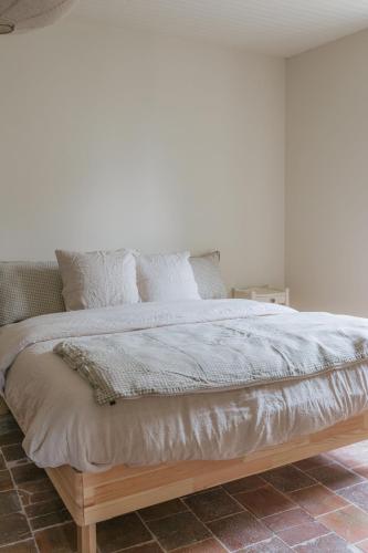 a large bed with white sheets and pillows at Gîte Guillaumand in Pompignan