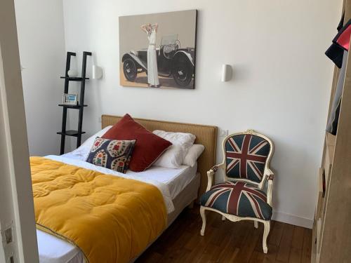 Cette chambre comprend un lit avec une couverture jaune et une chaise. dans l'établissement Maison hyper centre 2 pas de la plage, à Dinard