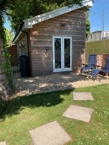 a shed with two chairs in a yard at Y Caban-The Cabin-2 Guests-Private Parking-Fast WIFI in Llanelli