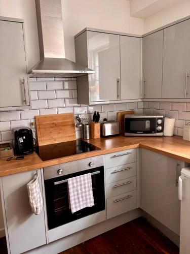 a kitchen with white cabinets and a stove top oven at Catherine Hill House Grade 2 Listed Apartment, Frome in Frome