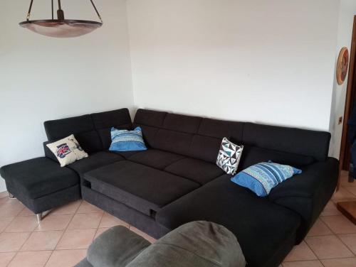 a black couch in a living room with pillows on it at Appartamento Colliwood in SantʼOmero