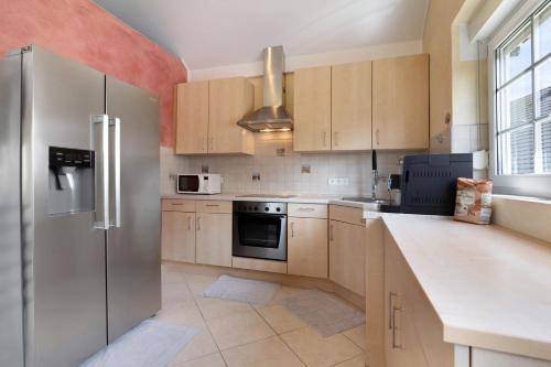 a kitchen with wooden cabinets and a stainless steel refrigerator at Gästesuite in Kehl am Rhein