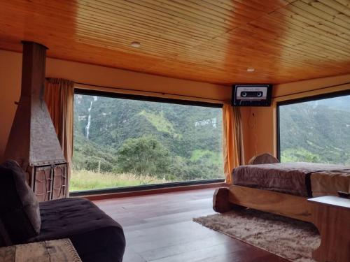 a bedroom with a large window with a view of the mountains at Choachi casa colibri in Choachí