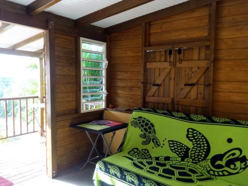 a green couch in a room with a balcony at Gites Les Palmiers in Bouillante