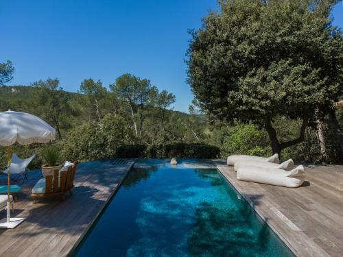 a pool with chairs and an umbrella and a tree at Villa d'Artiste en pleine pinède à 10 min d'Aix in Meyreuil