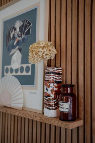 a shelf with a jar and a vase with flowers at Villa d'Artiste en pleine pinède à 10 min d'Aix in Meyreuil