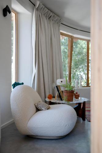 a white chair sitting in a room with a table at Villa d'Artiste en pleine pinède à 10 min d'Aix in Meyreuil