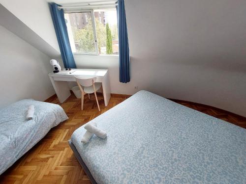 a bedroom with two beds and a desk and a window at Casa El Viso in Madrid