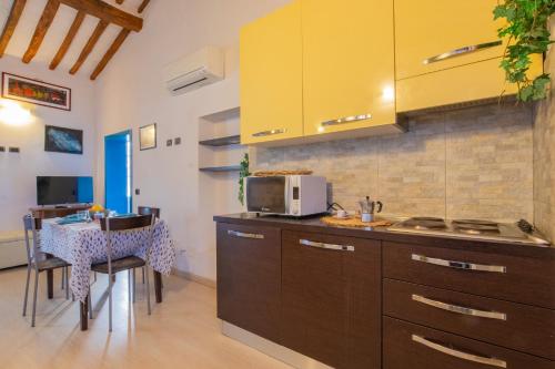 a kitchen with brown cabinets and a table with a microwave at Casa Di Dea in Porto Azzurro