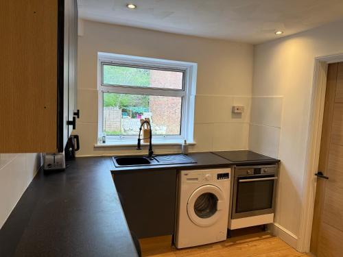 a kitchen with a sink and a washing machine at Apartment close to London Stansted airport in Great Parndon