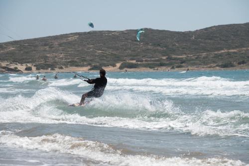 a man riding a wave on a surfboard in the ocean at Asimenis Cottages in Kattavía