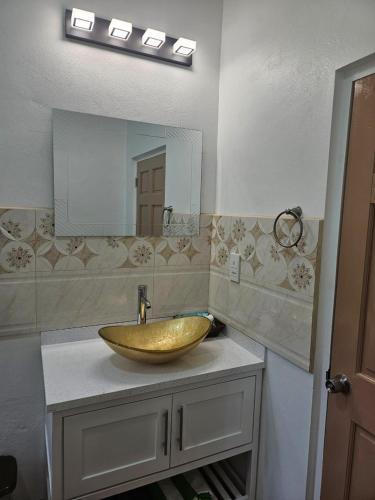 a bathroom with a gold sink and a mirror at Agape Suites-Room 3- 1st Floor in Soufrière