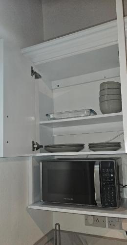 a kitchen with a microwave and some plates and pans at Agape Suites-Room 3- 1st Floor in Soufrière