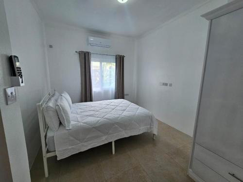 a bedroom with a white bed with a window at Agape Suites-Room 3- 1st Floor in Soufrière