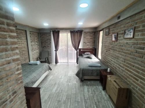 a bedroom with two beds and a brick wall at Hosteria y Cabañas Malloa - Naturaleza y Desconexión in Caracoles