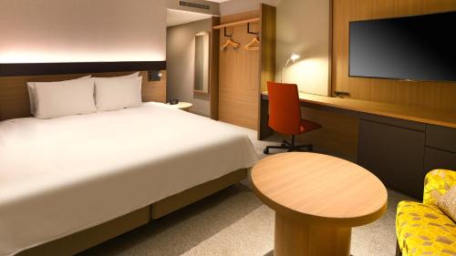 a hotel room with a bed and a table and a tv at ANA Crowne Plaza Niigata by IHG in Niigata