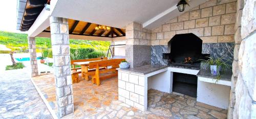 an outdoor patio with a fireplace and a wooden bench at Villa Ana with a private pool on a 3000m2 property in Čvrljevo