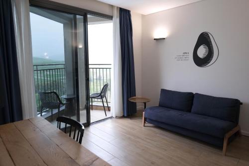a living room with a blue couch and a table at Kfar Giladi Hotel in Kefar Gil‘adi