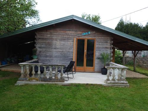 a log cabin with a table and a chair in front of it at Chambre d'hôtes Juste-Confortable in Fleurey-lès-Lavoncourt