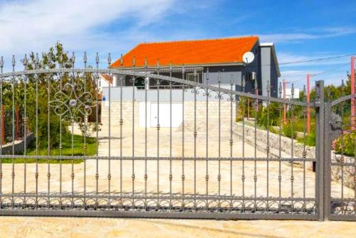 a gate in front of a building with an orange roof at Villa Ana with a private pool on a 3000m2 property in Čvrljevo