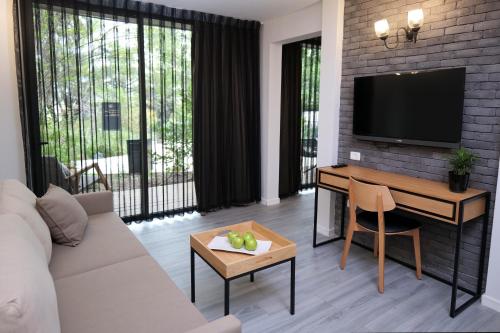 a living room with a couch and a desk and a tv at Kfar Giladi Hotel in Kefar Gil‘adi