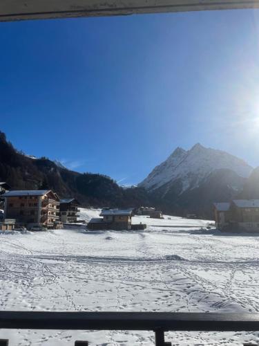a snow covered field with houses and mountains in the background at Grand appartement calme avec vue, balcon et parking couvert in Evolène