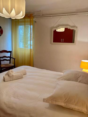 - une chambre avec un lit blanc et une serviette dans l'établissement Casa Duhamel - T2 Paisible avec Stationnement - Proche Centre-ville Brive, à Brive-la-Gaillarde