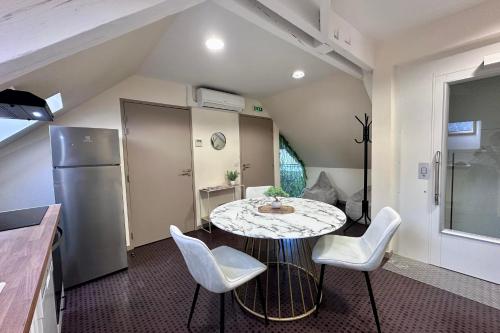 une cuisine avec une table, des chaises et un réfrigérateur dans l'établissement Casa Foch - T3 pour 3 personnes - Parking - Proche Hyper Centre, à Brive-la-Gaillarde