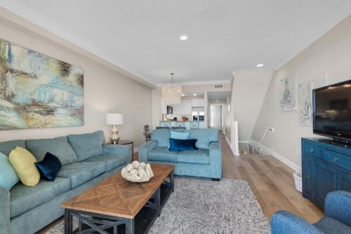 a living room with blue couches and a tv at Beach Baby by Gulf Coast Getaways in Navarre