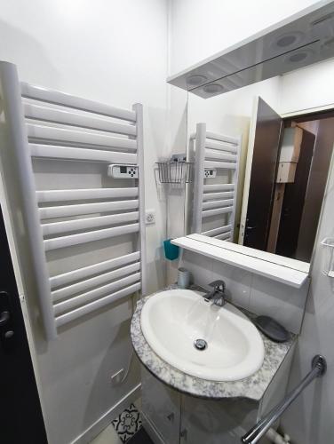 une salle de bain blanche avec un lavabo et un miroir dans l'établissement Le Cardinal, à La Rochelle