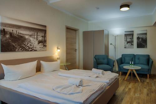 a hotel room with a bed and two blue chairs at Zur Eiche in Ahlbeck