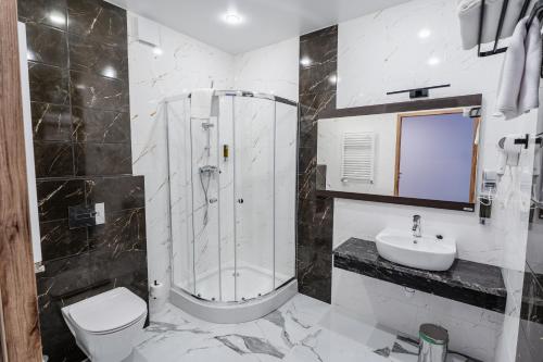 a bathroom with a shower and a toilet and a sink at Hotel - Restauracja SŁONECZNA in Gostyń