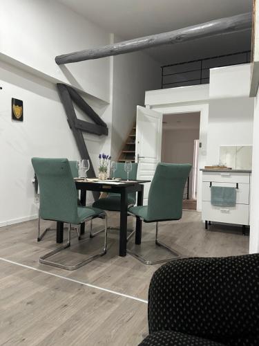a dining room with a table and green chairs at Le nid du 4 in Épernay