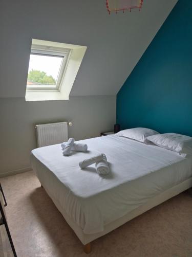 Cet appartement comprend une chambre dotée d'un lit avec un mur bleu et une fenêtre. dans l'établissement Pôle Européen du Cheval - Gîte de la Fromenterie, à Yvré-lʼÉvêque