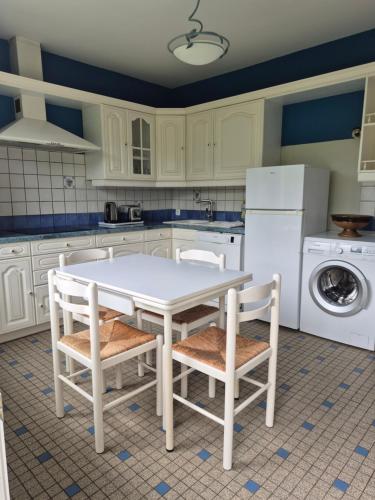 une cuisine avec une table blanche et deux chaises dans l'établissement Pôle Européen du Cheval - Gîte de la Fromenterie, à Yvré-lʼÉvêque