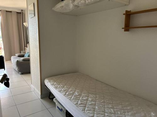- un petit lit dans une chambre avec un canapé dans l'établissement Studio avec Piscine, Tennis et Accès Direct Plage - 3 Couchages, Terrasse, Parking - Bormes-les-Mimosas - FR-1-251-702, à Bormes-les-Mimosas